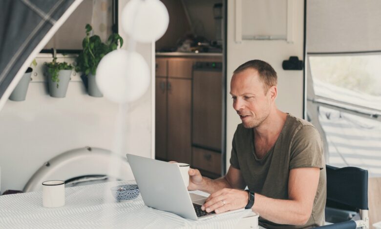 Image of a man drinking coffee while using his computer outside his RV